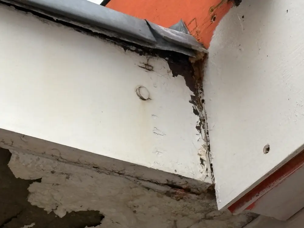 Afbladderende verf en betonschade aan een luifel bij een afvoer